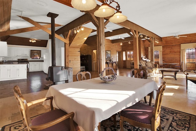 dining space featuring vaulted ceiling with beams, wooden walls, sink, and ceiling fan