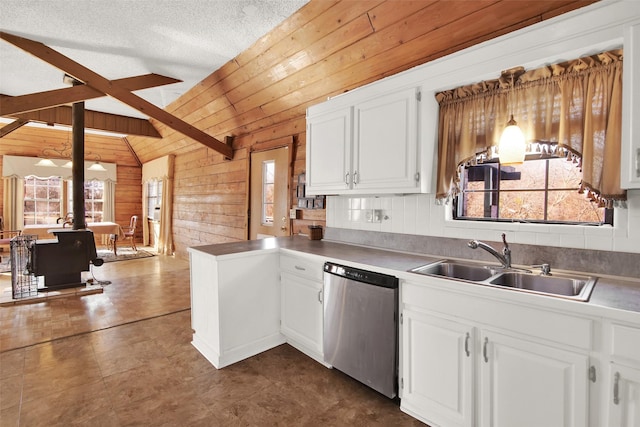 kitchen with white cabinetry, stainless steel dishwasher, and wood walls