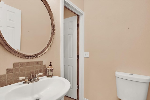 bathroom featuring toilet, sink, and backsplash