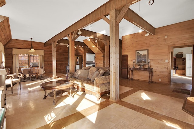 living room with track lighting, wooden walls, and light parquet floors