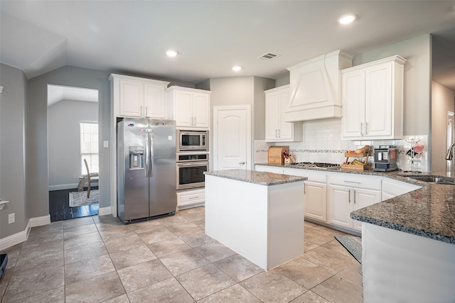 kitchen with custom exhaust hood, stainless steel appliances, sink, a center island, and white cabinetry