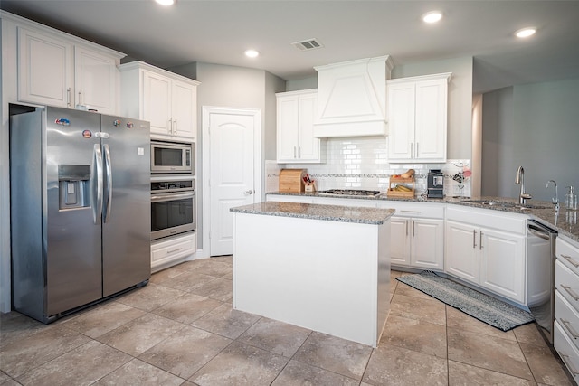 kitchen with sink, decorative backsplash, custom range hood, appliances with stainless steel finishes, and white cabinetry