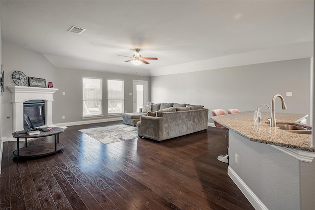 living room with dark hardwood / wood-style floors, ceiling fan, and sink