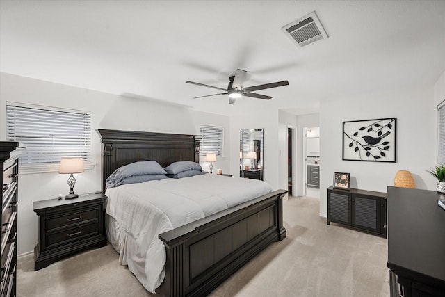 carpeted bedroom with ensuite bath and ceiling fan