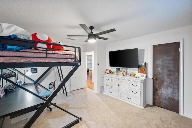 carpeted bedroom featuring ceiling fan and a textured ceiling