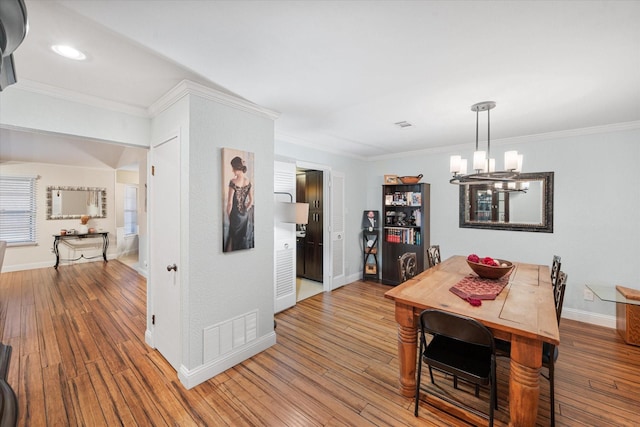 dining area featuring hardwood / wood-style flooring, crown molding, and a notable chandelier