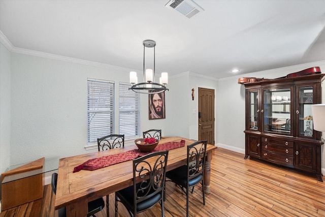 dining area featuring light hardwood / wood-style floors, an inviting chandelier, and ornamental molding