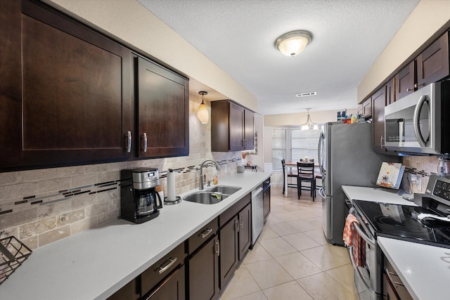 kitchen with sink, hanging light fixtures, decorative backsplash, light tile patterned flooring, and appliances with stainless steel finishes