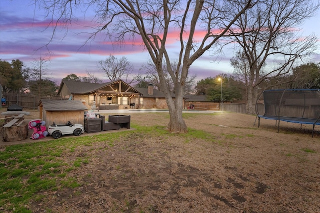 yard at dusk featuring a trampoline