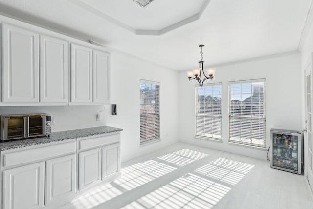 kitchen with dark stone counters, white cabinets, pendant lighting, and a notable chandelier