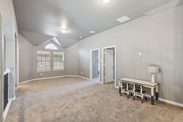 carpeted spare room featuring vaulted ceiling