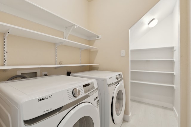 clothes washing area with separate washer and dryer and light hardwood / wood-style flooring