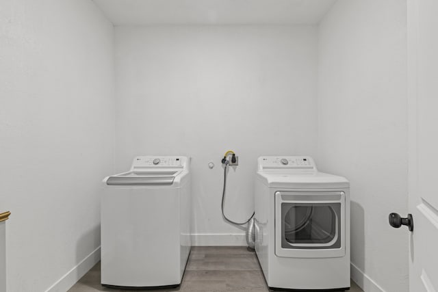 washroom with light wood-type flooring and washing machine and dryer