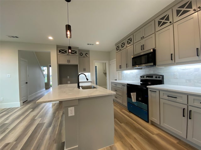 kitchen with sink, gray cabinetry, electric range, a center island with sink, and decorative light fixtures