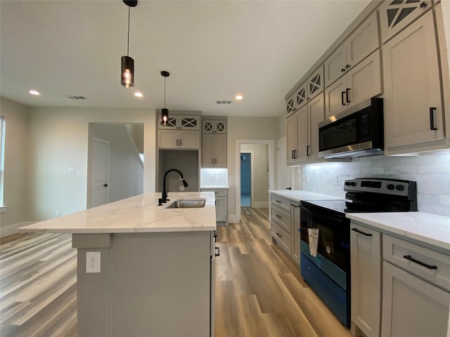 kitchen featuring decorative light fixtures, sink, gray cabinetry, black range with electric stovetop, and a center island with sink