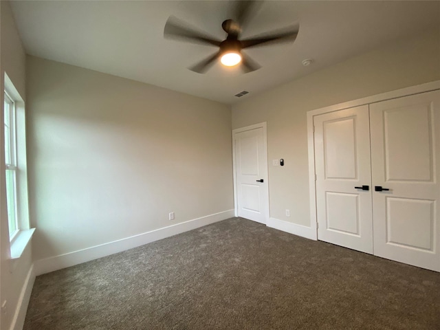 unfurnished bedroom featuring ceiling fan, a closet, and dark colored carpet