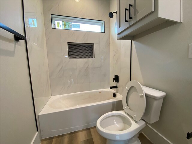 bathroom with hardwood / wood-style flooring, toilet, and tiled shower / bath combo