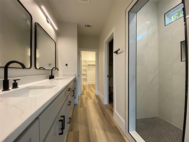 bathroom featuring vanity, hardwood / wood-style floors, and a tile shower