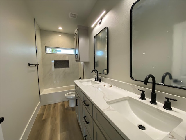 full bathroom with tiled shower / bath, hardwood / wood-style floors, vanity, and toilet