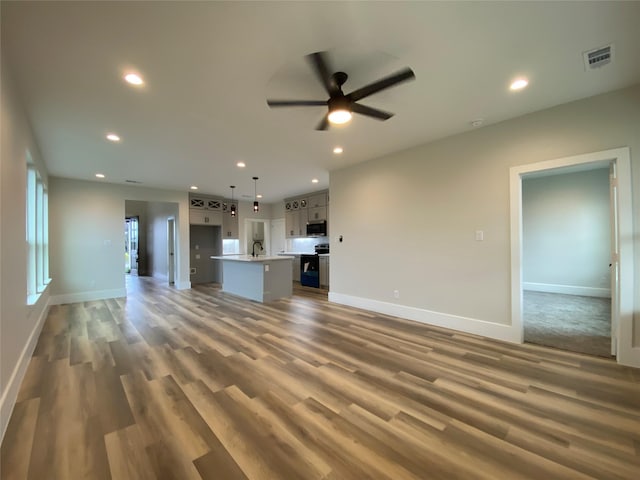 unfurnished living room featuring ceiling fan, sink, and hardwood / wood-style floors