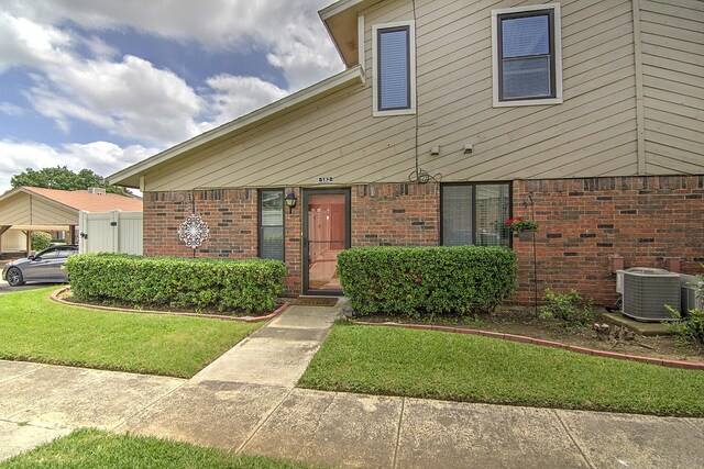 view of front of house with central AC unit and a front yard