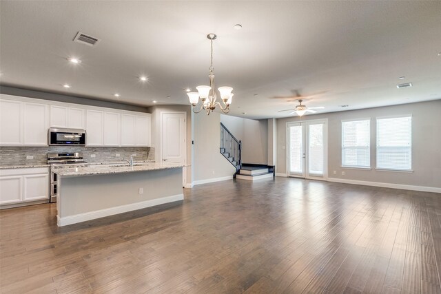 kitchen with backsplash, white cabinets, a center island with sink, hanging light fixtures, and stainless steel appliances