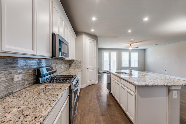 kitchen with stainless steel appliances, white cabinetry, a center island with sink, and sink