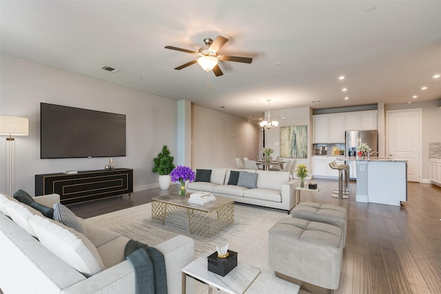 living room with hardwood / wood-style flooring and ceiling fan with notable chandelier