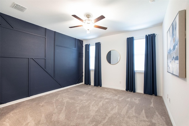 spare room with ceiling fan and light colored carpet