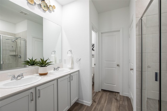 bathroom featuring vanity, hardwood / wood-style floors, a shower with shower door, and toilet