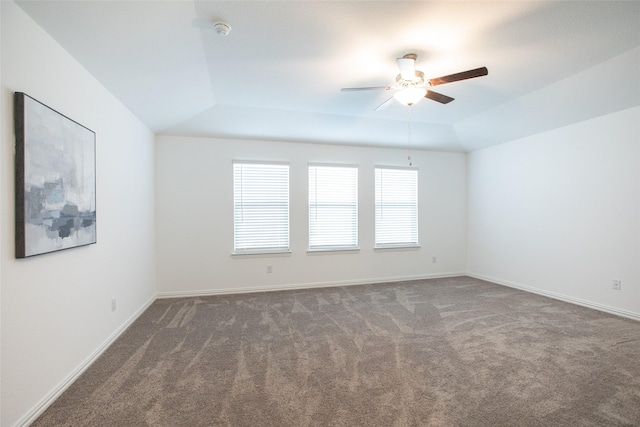 unfurnished room with a tray ceiling, dark carpet, lofted ceiling, and ceiling fan