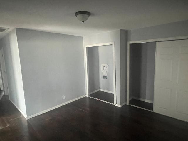 unfurnished bedroom with dark wood-type flooring and a closet