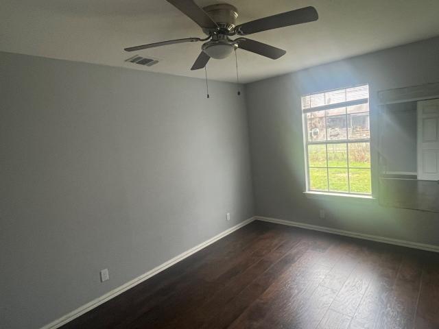 unfurnished room with ceiling fan and dark wood-type flooring