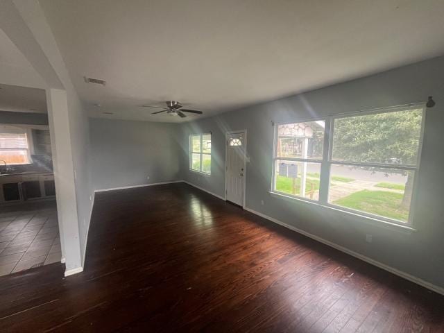 unfurnished living room featuring ceiling fan and dark hardwood / wood-style floors