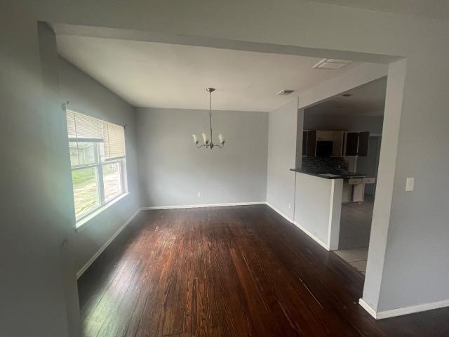 unfurnished dining area with dark hardwood / wood-style flooring and a chandelier