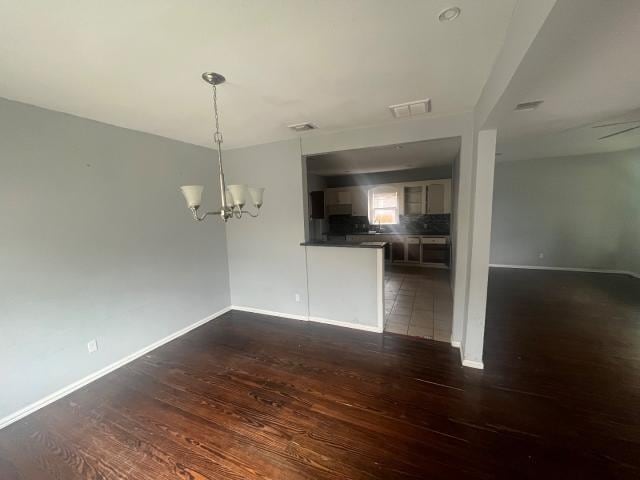 interior space featuring ceiling fan with notable chandelier and dark wood-type flooring