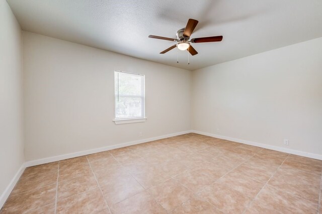 tiled empty room featuring ceiling fan and a textured ceiling