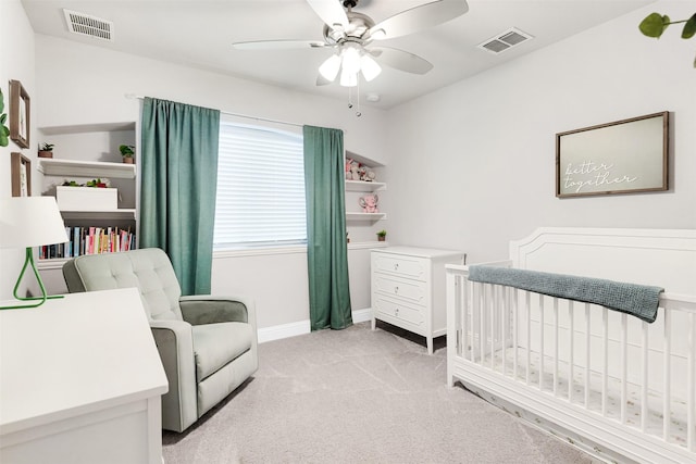 bedroom with ceiling fan, a crib, and light carpet