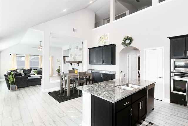 kitchen featuring appliances with stainless steel finishes, high vaulted ceiling, a kitchen island with sink, and sink