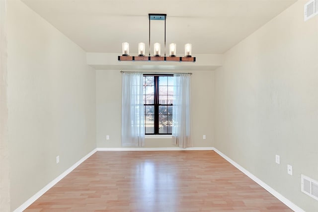 unfurnished dining area featuring light hardwood / wood-style floors and a notable chandelier