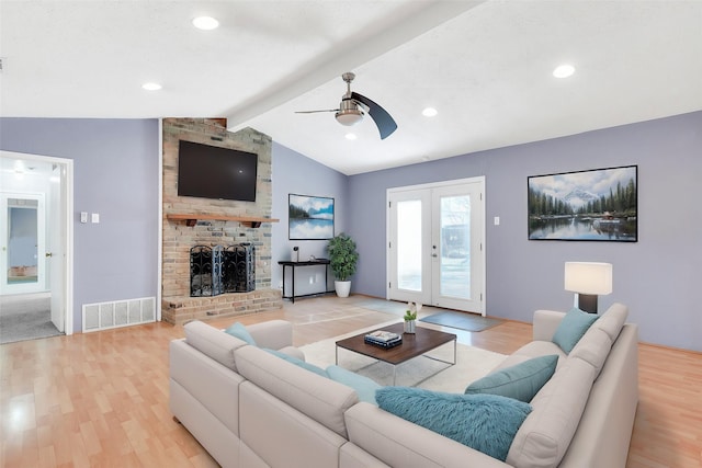 living room with ceiling fan, french doors, a brick fireplace, lofted ceiling with beams, and light hardwood / wood-style floors