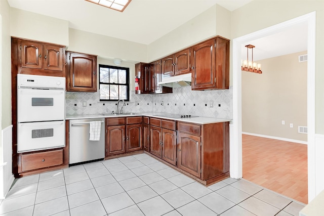 kitchen with sink, hanging light fixtures, stainless steel dishwasher, light tile patterned floors, and double oven