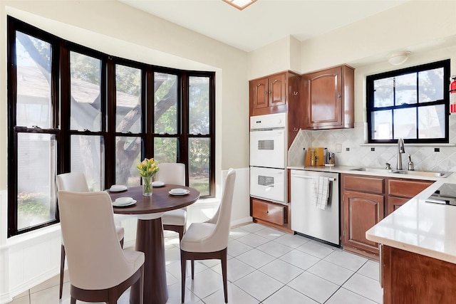 kitchen with stainless steel dishwasher, a healthy amount of sunlight, sink, and double oven