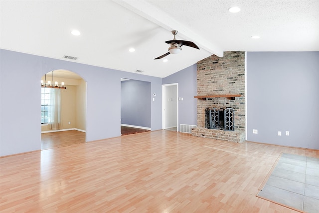 unfurnished living room with a textured ceiling, ceiling fan, lofted ceiling with beams, light hardwood / wood-style flooring, and a fireplace