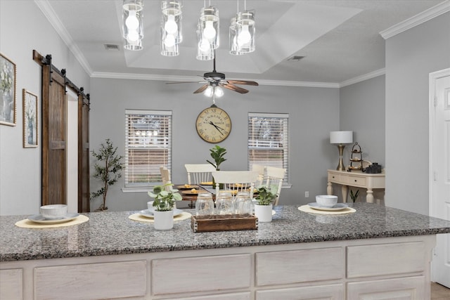 interior space featuring stone counters, ornamental molding, and a barn door