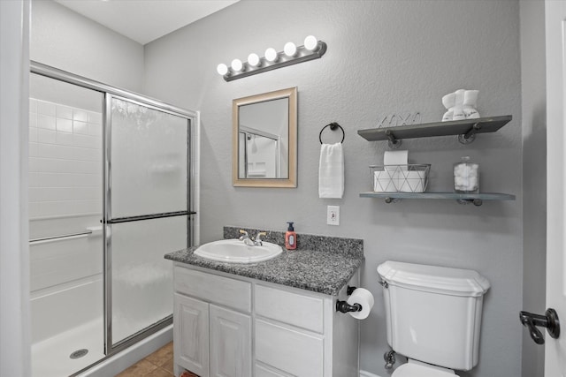 bathroom with tile patterned floors, vanity, toilet, and a shower with shower door