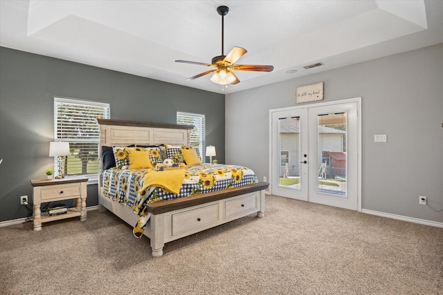 carpeted bedroom featuring ceiling fan, a tray ceiling, access to outside, and french doors