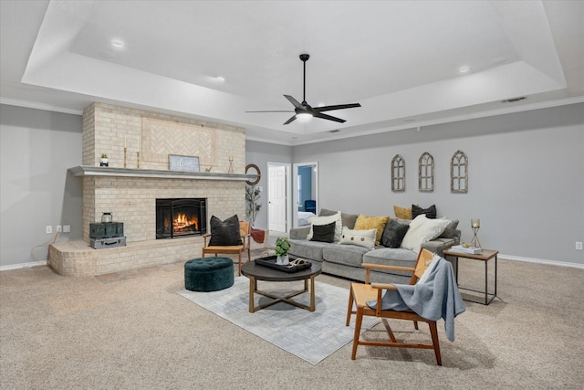 living room featuring ceiling fan, carpet flooring, a fireplace, and a tray ceiling