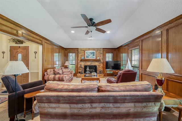 living room with ceiling fan, a healthy amount of sunlight, wooden walls, and vaulted ceiling