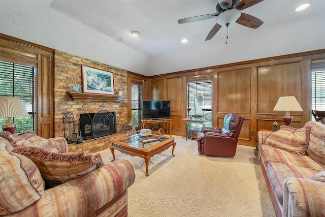 carpeted living room with ceiling fan, a brick fireplace, a textured ceiling, lofted ceiling, and wooden walls